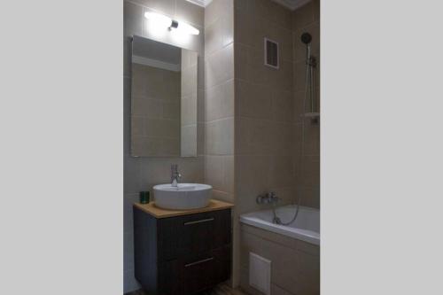 a bathroom with a sink and a tub and a mirror at Beautiful air-conditioned apartment in the centre in Debrecen