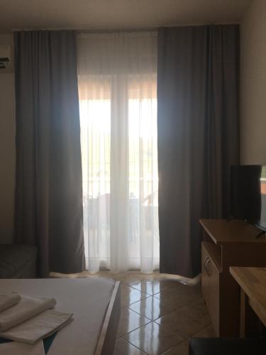 a bedroom with a bed and a window with curtains at Apartments MAMPAS in Neum