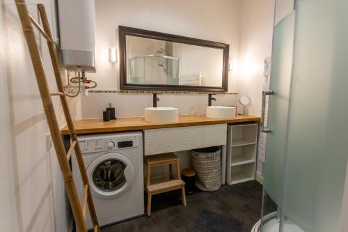 une salle de bain avec un lavabo et une machine à laver dans l'établissement Au dessus des toits, à Cauterets