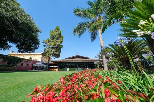 a garden in front of a building with palm trees and flowers at Hotel Mas La Boella in La Canonja