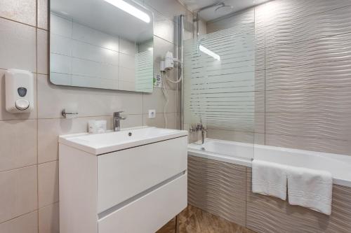 a white bathroom with a sink and a tub at Optima Collection Miramar Chornomorsk in Chornomorsk