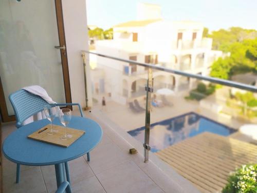 a table with two wine glasses on top of a balcony at Apartamentos Villa Primera in Cala Figuera