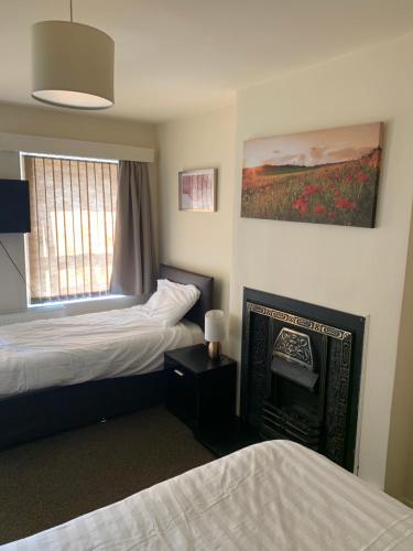 ハダーズフィールドにあるIvy Green innのベッド2台と暖炉付きのホテルルームです。