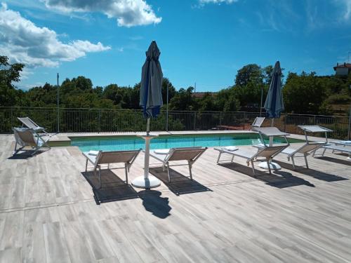 a pool with chairs and a table with a umbrella at Da Fabiana in Bossolasco