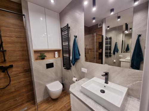 a bathroom with a white sink and a toilet at Apartament Fredry 2 PREMIUM KLIMA in Kołobrzeg