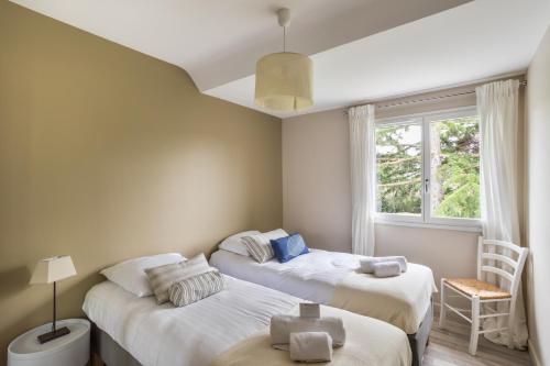 two beds in a room with a window at La Déferlante - Maison familiale à Cancale in Cancale
