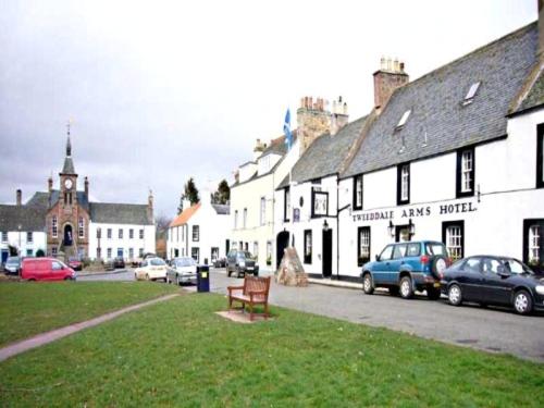 una ciudad con coches estacionados en el césped y edificios en Tweeddale Arms Hotel, en Gifford