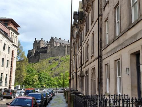 uma rua com carros estacionados e um castelo ao fundo em Edinburgh Nine em Edimburgo