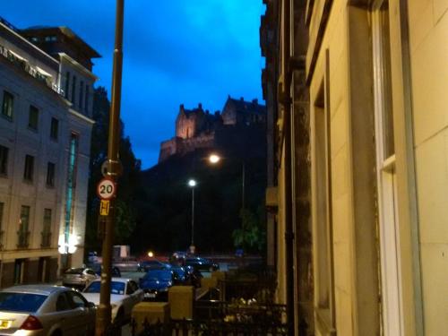 uma rua da cidade com um castelo ao fundo à noite em Edinburgh Nine em Edinburgo