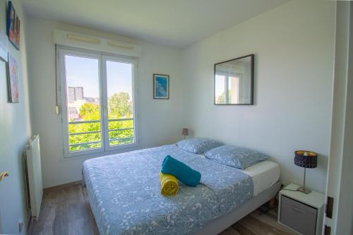 a bedroom with a bed with blue pillows and a window at Métro 12, Stade De France, Parking, Balcon, 45m2, View, in Aubervilliers