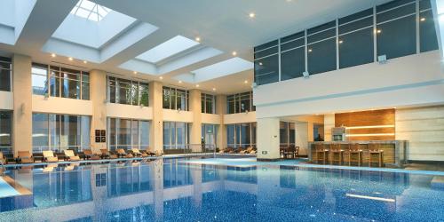 a large swimming pool in a building with windows at HUALUXE Ningbo Harbor City, an IHG Hotel in Ningbo