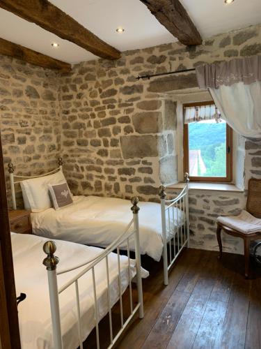 - 2 lits dans une chambre avec un mur en pierre dans l'établissement Maison de Bois Royale, à Royère-de-Vassivière