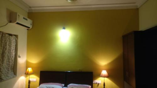 a bedroom with a bed and two lights on the wall at Samrat Hotel in Ludhiana