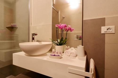 a bathroom with a sink and a toilet and flowers at Serena al Casalone - Arceno Rentals Club in San Gusmè