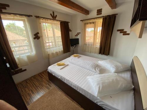 - une chambre avec un lit doté de draps blancs et de fenêtres dans l'établissement Casa Floare de Colt, à Cârţişoara