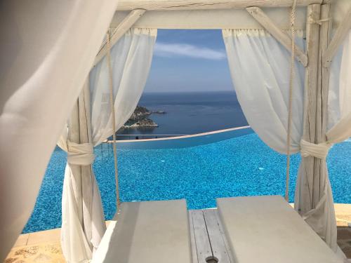 a room with a window with a view of the ocean at Petani Bay Hotel - Adults Only in Vovikes