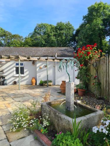 a garden with a fountain in front of a house at Brookvale in Wellingtonbridge
