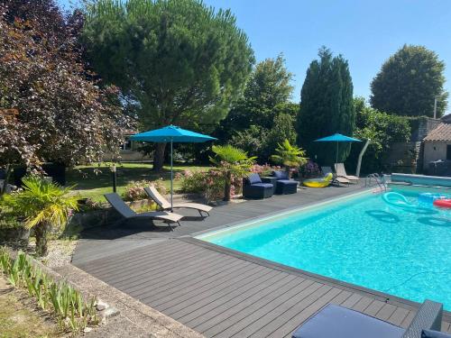 une piscine avec des chaises et des parasols à côté dans l'établissement Gîte Le Travezay, à Courcoué