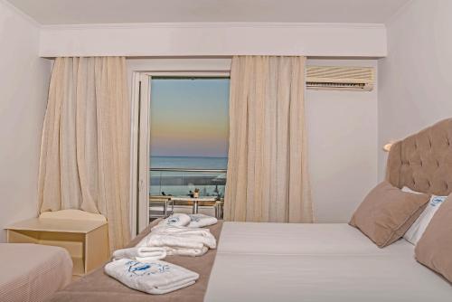 a bedroom with a bed with towels and a window at Denise Beach Hotel in Laganas