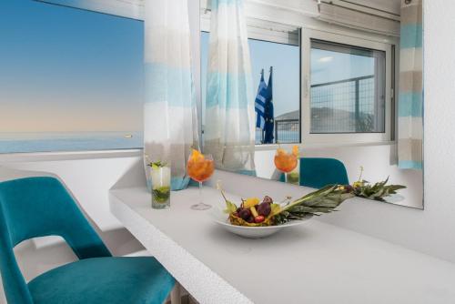 a table with blue chairs and a bowl of fruit on it at Denise Beach Hotel in Laganas