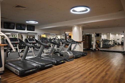 a gym with a row of treadmills and ellipticals at Aleksandar Palace Hotel Congress Center & SPA in Skopje