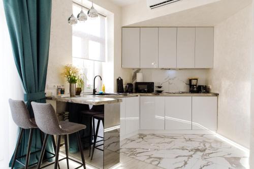a kitchen with white cabinets and a marble floor at Panorama Luxury Apartment in The House with a Spire, a historical building in the city centre in Kharkiv