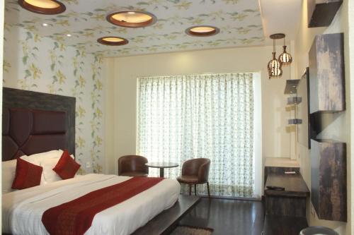 a bedroom with a bed and a window and a table at S S INTERNATIONAL in Dalhousie