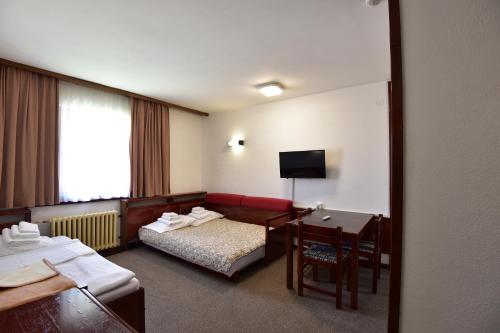 a hotel room with a bed and a desk and a table at Apartments JAT Kopaonik in Kopaonik