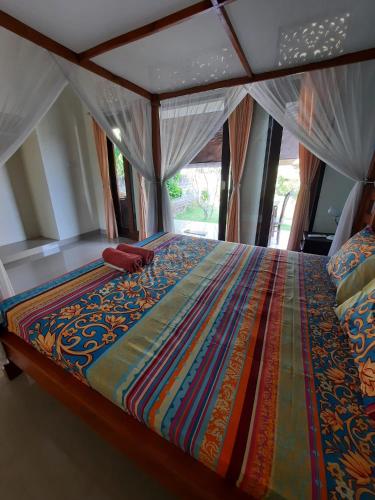 a bed with a colorful comforter in a room at Bumbung Bungalows in Amed