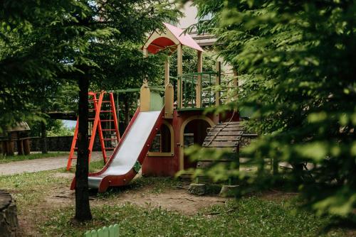 a playground with a slide in front of a house at Kamyanka in Mizhhirʼʼya