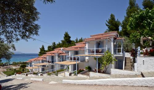 a row of houses on a hill next to the ocean at Milia Apartments in Paralia Milia