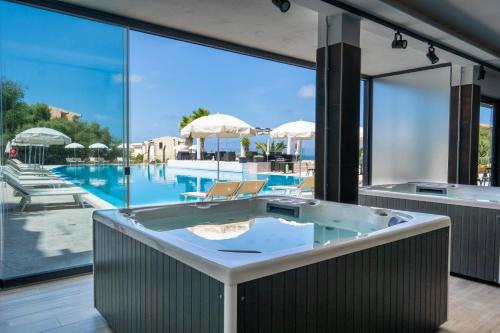 a jacuzzi tub in a room with a pool at Horizon Hotel Badesi in Badesi