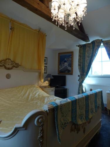 a bedroom with a bed and a chandelier at Chateau du Mesnil in La Vieille-Lyre