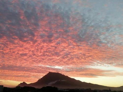 a mountain under a cloudy sky at sunset at Just Chill Betty's Bay in Bettyʼs Bay