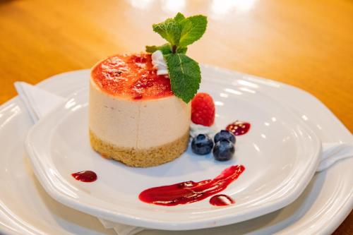 a piece of cake on a white plate with berries at BON Hotel Bloemfontein Central in Bloemfontein