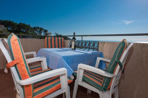 a table and chairs with a table and a bottle of wine at Apartments Marina in Sveti Stefan