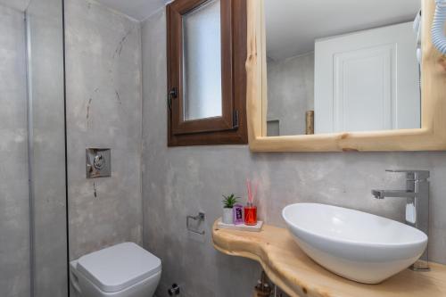 La salle de bains est pourvue d'un lavabo, de toilettes et d'un miroir. dans l'établissement Melina's Cozy Apartment, à Triovasálos