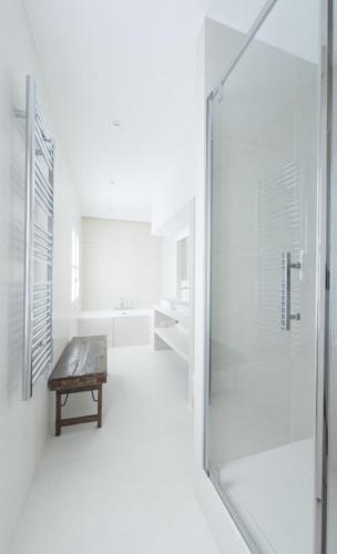 La salle de bains est pourvue d'une douche en verre et d'un banc. dans l'établissement Rue Charlot Le Marais, à Paris