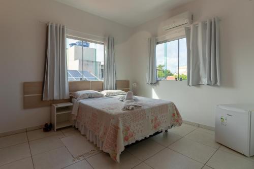 a bedroom with a bed and two windows at Cantinho da Melão in Maragogi