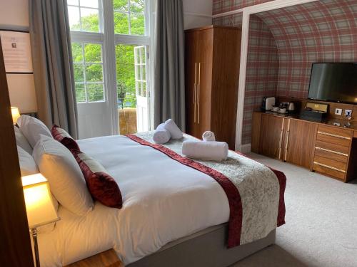 a bedroom with a bed with a television and a window at The Craigie Hotel in Penicuik