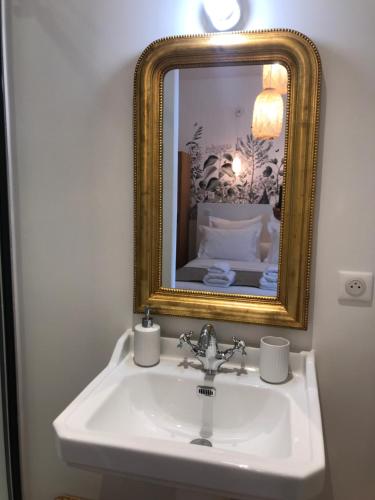 a bathroom with a sink and a gold mirror at Maison Caju - La Rochelle in La Rochelle