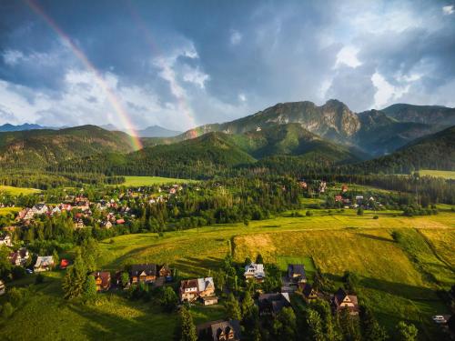 um arco-íris sobre uma pequena cidade num vale com montanhas em Zasypane Premium House & Sauna in Zakopane by Renters Prestige em Zakopane