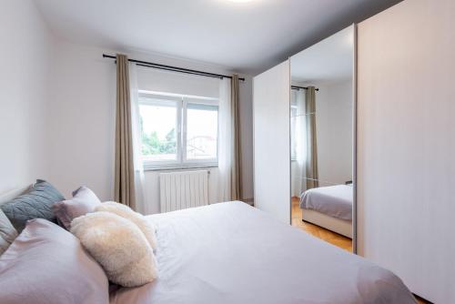 a bedroom with a white bed and a large mirror at Apartman Justina Medulin for 2 person in Medulin