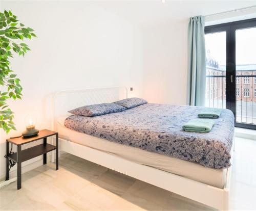 a white bedroom with a bed and a window at The Antwerp Marble Lodge in Antwerp