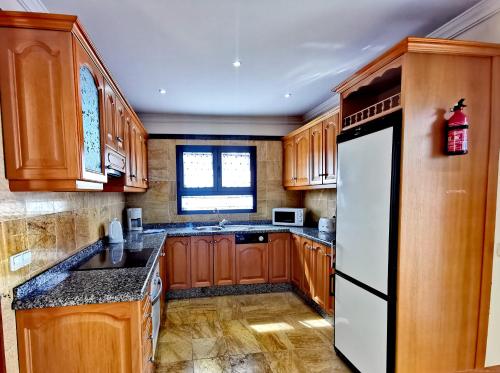 - une cuisine avec des placards en bois et un réfrigérateur blanc dans l'établissement Villa Lidia, à Playa Blanca