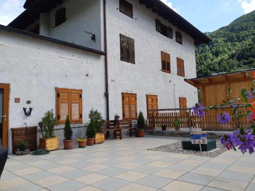 een groot wit gebouw met houten deuren en potplanten bij casa vacanze in Cogolo
