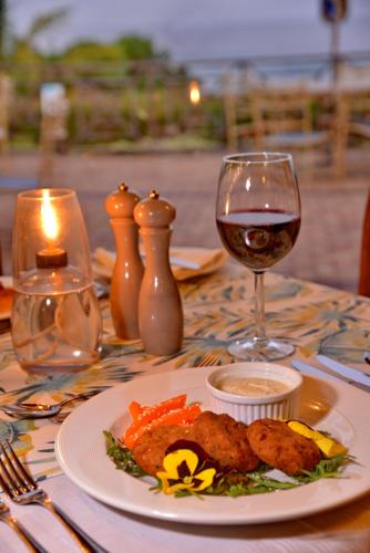 a table with a plate of food and a glass of wine at Pumula Beach Hotel in Umzumbe