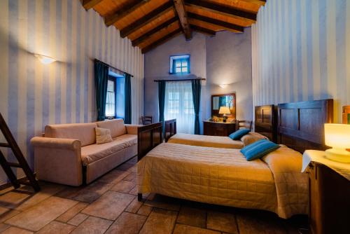 a bedroom with two beds and a couch and a chair at Agriturismo La Casa Degli Ospiti in Dolegna del Collio