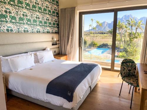 a hotel room with a bed and a large window at Ludus Magnus Boutique Hotel in Franschhoek