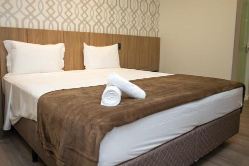 a hotel room with a bed with two towels on it at Hotel Zunino in Palhoça